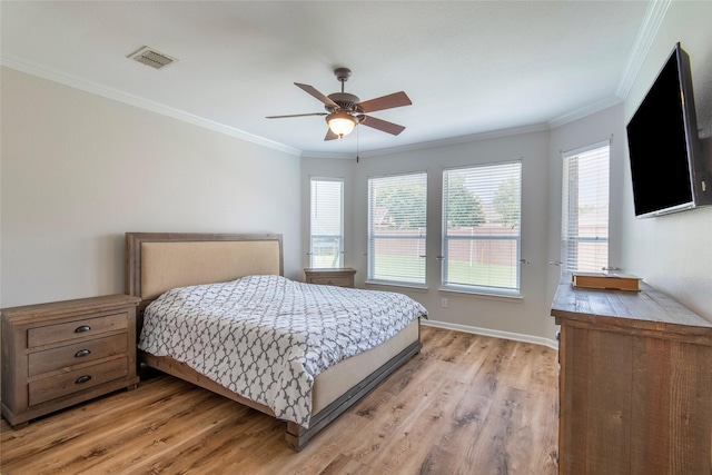 bedroom with light wood-style floors, baseboards, visible vents, and ornamental molding