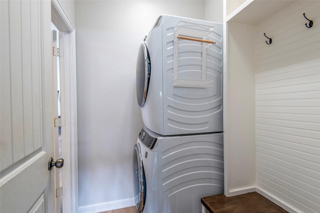 laundry area with laundry area, stacked washing maching and dryer, and baseboards