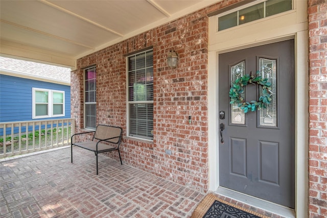 property entrance featuring a porch and brick siding