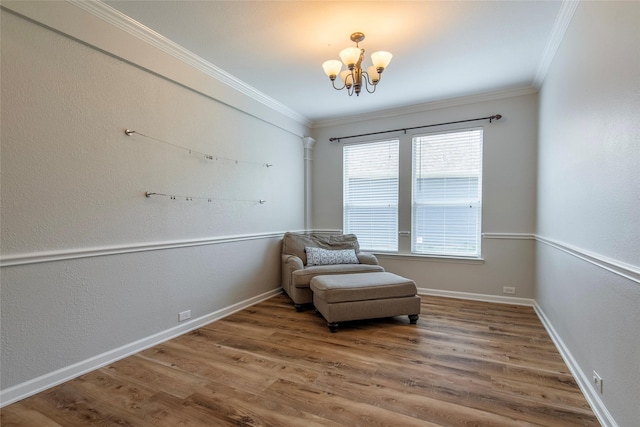 sitting room with a notable chandelier, crown molding, baseboards, and wood finished floors