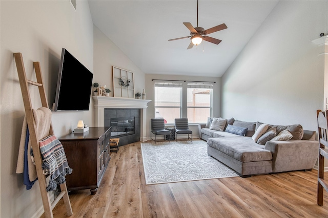 living area featuring high vaulted ceiling, a fireplace, light wood-style flooring, and a ceiling fan