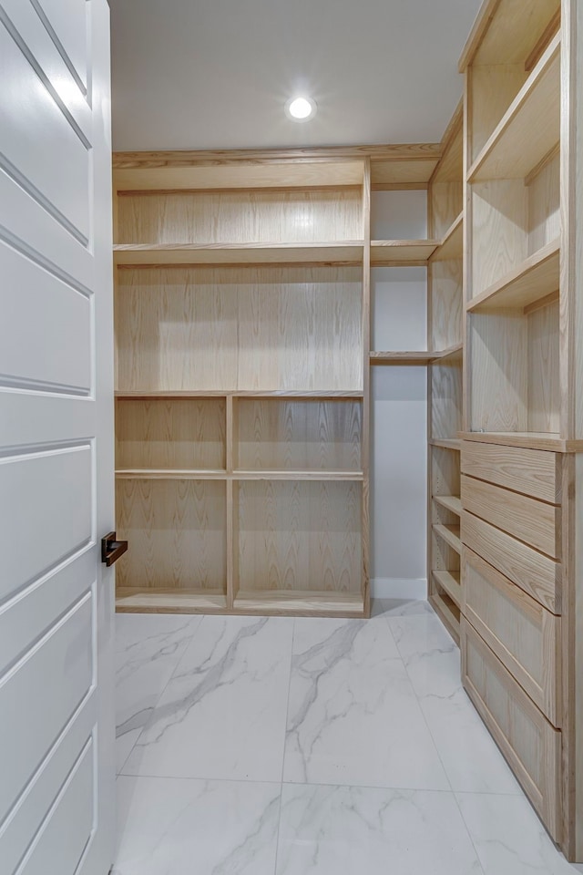 walk in closet featuring marble finish floor