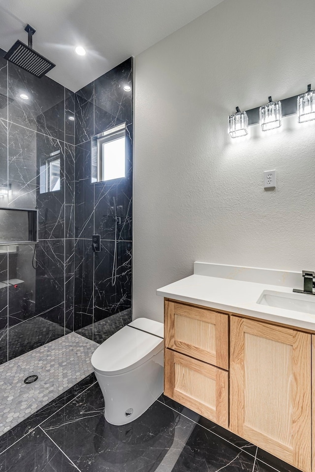 bathroom featuring marble finish floor, a marble finish shower, a textured wall, toilet, and vanity