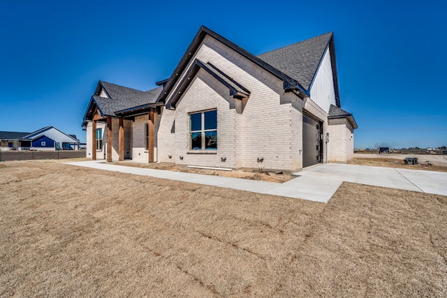 view of front of home featuring concrete driveway, brick siding, roof with shingles, and an attached garage