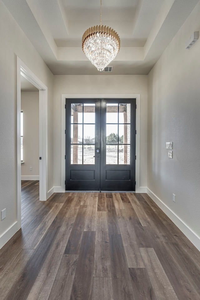 entryway featuring dark wood-style floors, a tray ceiling, visible vents, and a notable chandelier