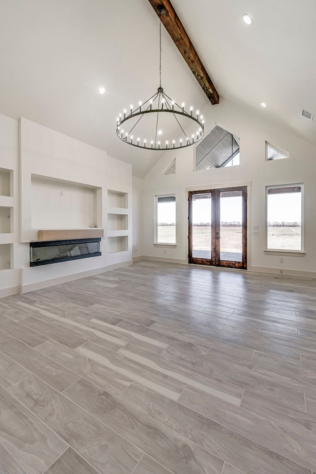 unfurnished living room with built in features, a glass covered fireplace, french doors, high vaulted ceiling, and beam ceiling