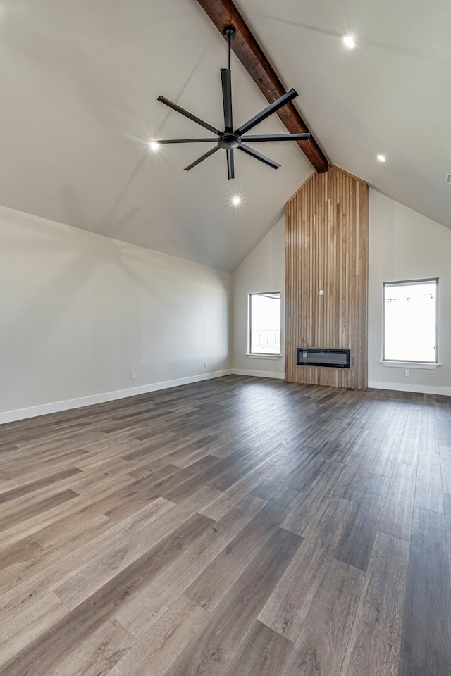 unfurnished living room with a wealth of natural light, a fireplace, beamed ceiling, and wood finished floors