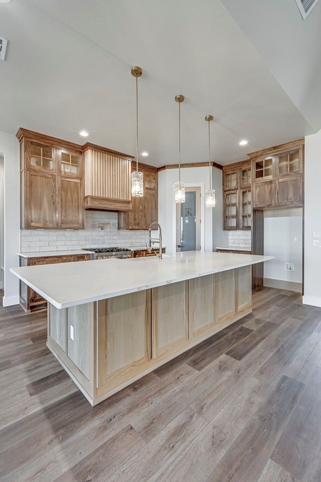 kitchen with a spacious island, tasteful backsplash, and wood finished floors