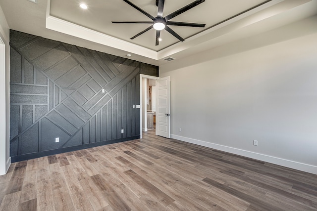 spare room with visible vents, baseboards, a raised ceiling, wood finished floors, and recessed lighting