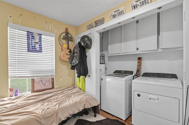 washroom featuring a textured ceiling, washing machine and dryer, and cabinet space