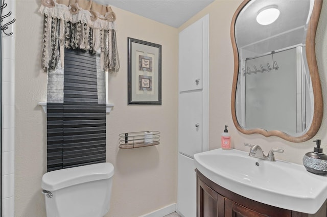 bathroom featuring a shower with door, vanity, and toilet