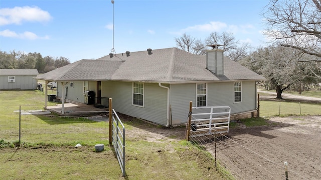 back of house with a yard, a chimney, a patio, a shingled roof, and fence