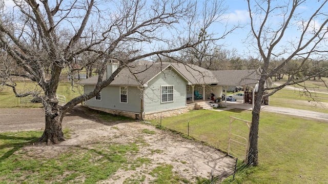 view of front of property featuring driveway, a shingled roof, fence, and a front lawn