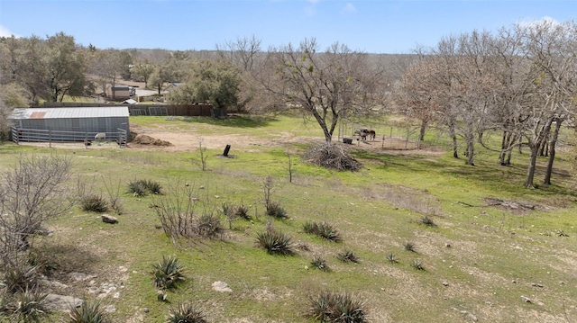 exterior space with a rural view, an outdoor structure, and fence