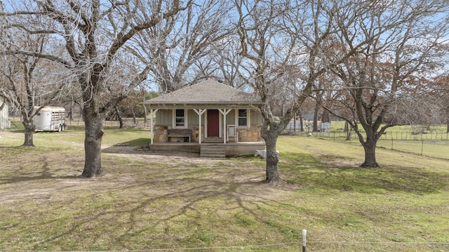 view of front of property featuring a shingled roof, stone siding, a porch, fence, and a front lawn