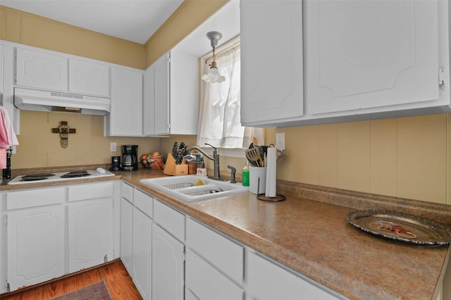 kitchen with white cabinets, white electric cooktop, a sink, and under cabinet range hood