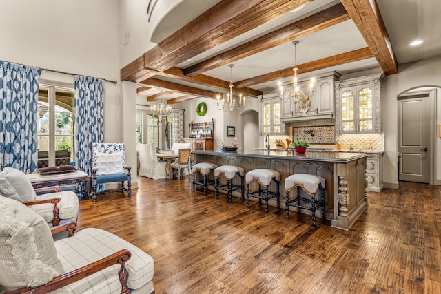 bar featuring hanging light fixtures, beam ceiling, decorative backsplash, dark wood-style floors, and an inviting chandelier