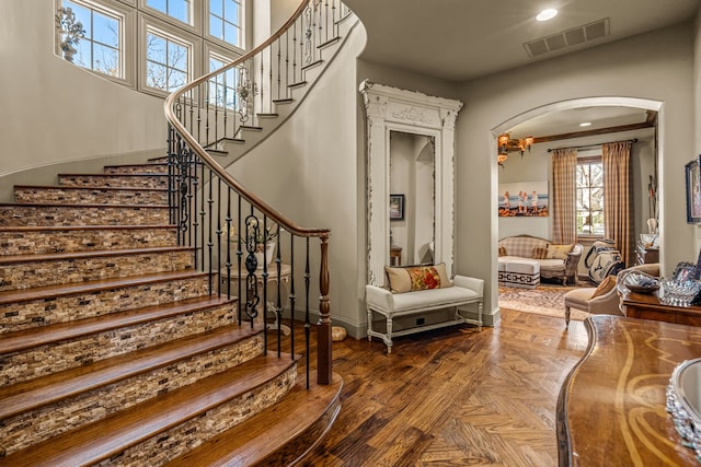 stairs featuring arched walkways, baseboards, visible vents, and recessed lighting