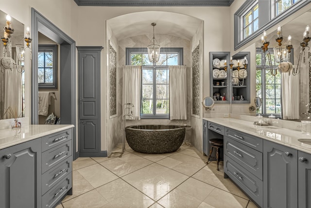 bathroom featuring lofted ceiling, a freestanding tub, vanity, and an inviting chandelier