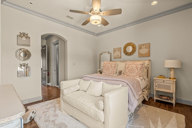 bedroom with arched walkways, wood finished floors, visible vents, baseboards, and ornamental molding