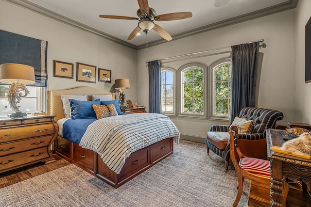 bedroom featuring ceiling fan, baseboards, crown molding, and wood finished floors