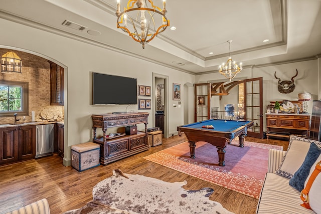 recreation room with visible vents, arched walkways, a raised ceiling, wood finished floors, and a notable chandelier