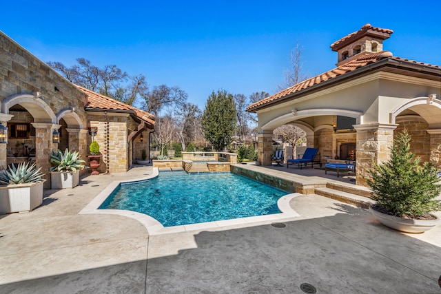 view of pool featuring a patio, a fireplace, and a pool with connected hot tub