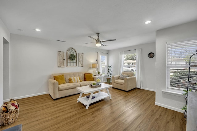 living room with recessed lighting, visible vents, baseboards, and wood finished floors