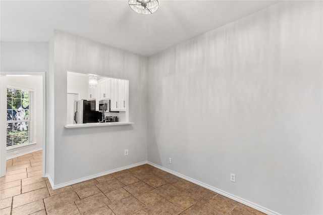 unfurnished room featuring stone finish floor and baseboards