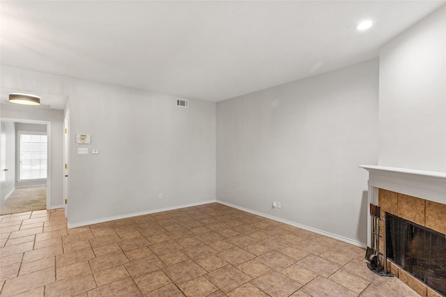 unfurnished living room with recessed lighting, a tiled fireplace, visible vents, and baseboards