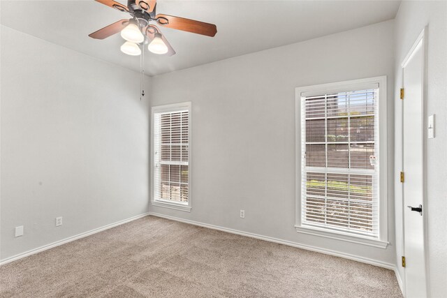 unfurnished room featuring carpet floors, a healthy amount of sunlight, baseboards, and a ceiling fan