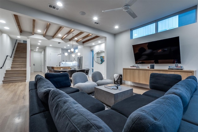 living room with light wood-style floors, beam ceiling, visible vents, and stairs