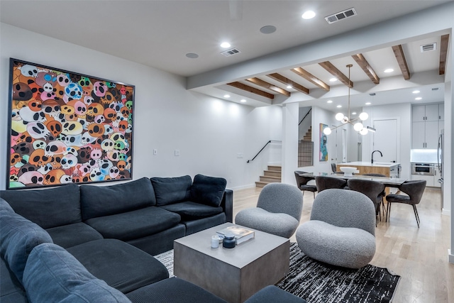 living room with light wood-type flooring, beam ceiling, visible vents, and stairs