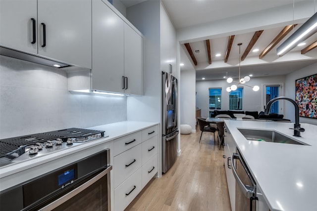 kitchen featuring a sink, stainless steel appliances, light countertops, light wood-style floors, and beam ceiling