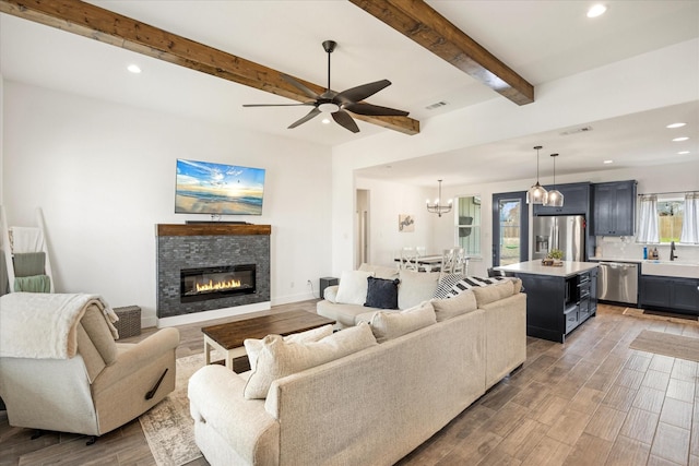 living area featuring light wood-type flooring, beam ceiling, visible vents, and recessed lighting