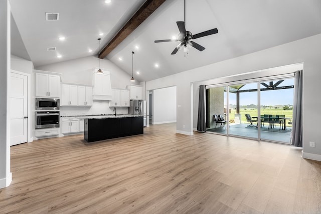 kitchen with white cabinetry, stainless steel appliances, beam ceiling, and open floor plan