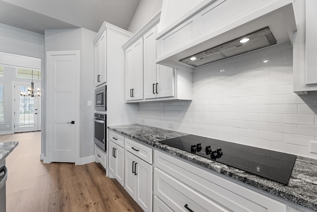 kitchen with white cabinets, decorative backsplash, wall chimney exhaust hood, wood finished floors, and stainless steel appliances