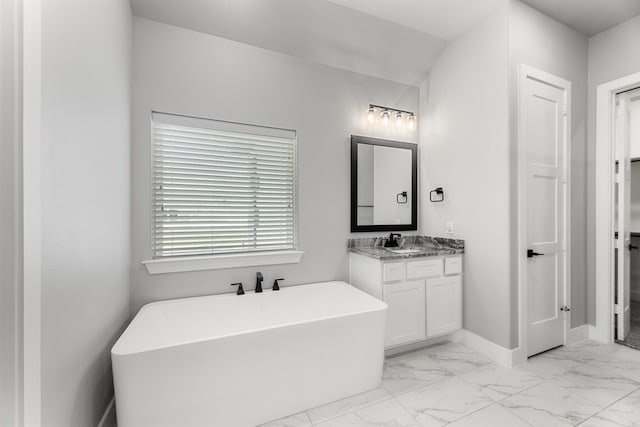 full bath featuring a freestanding bath, marble finish floor, vanity, and baseboards