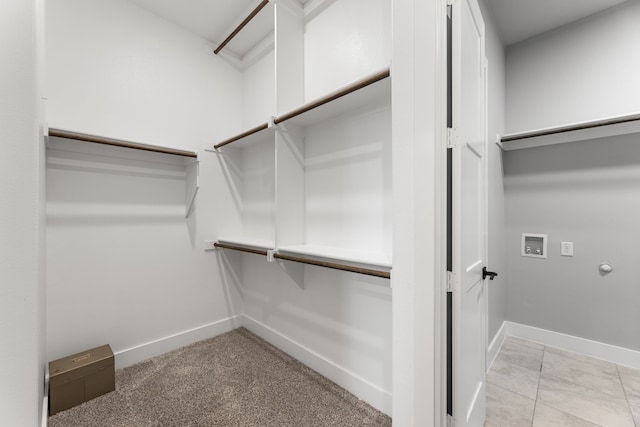 walk in closet with light carpet and light tile patterned flooring