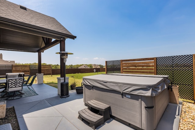 view of patio / terrace with a hot tub, a fenced backyard, and outdoor dining space