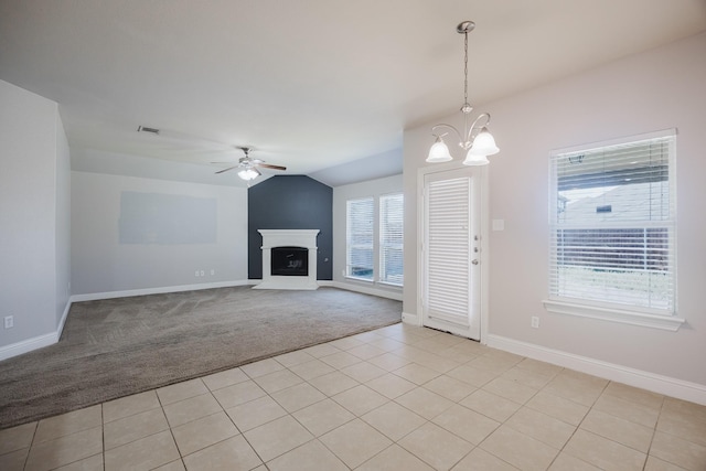 unfurnished living room featuring light colored carpet, ceiling fan with notable chandelier, a fireplace, baseboards, and vaulted ceiling