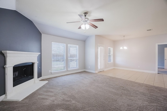 unfurnished living room featuring lofted ceiling, light colored carpet, a fireplace with raised hearth, baseboards, and ceiling fan with notable chandelier