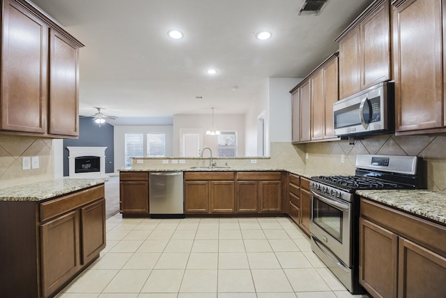 kitchen with visible vents, appliances with stainless steel finishes, a peninsula, a fireplace, and a sink