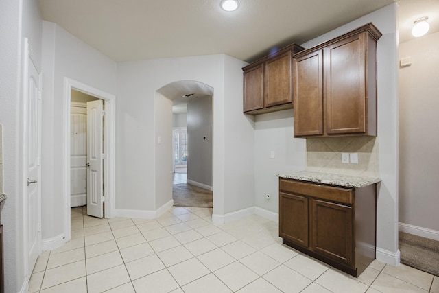 kitchen with baseboards, arched walkways, backsplash, and light tile patterned flooring