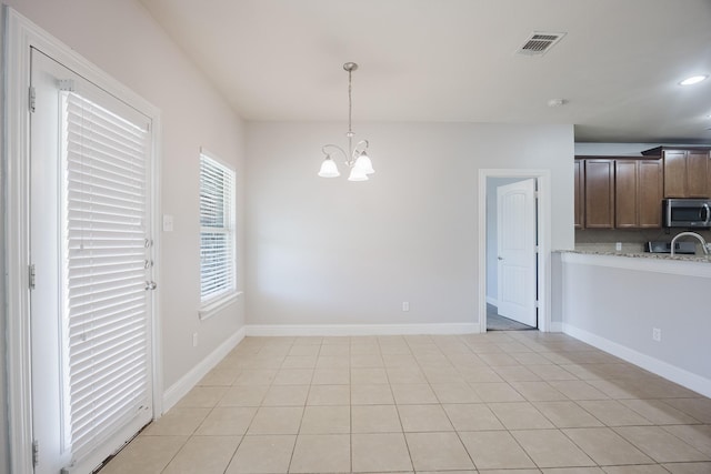 unfurnished dining area with a chandelier, visible vents, baseboards, and light tile patterned floors