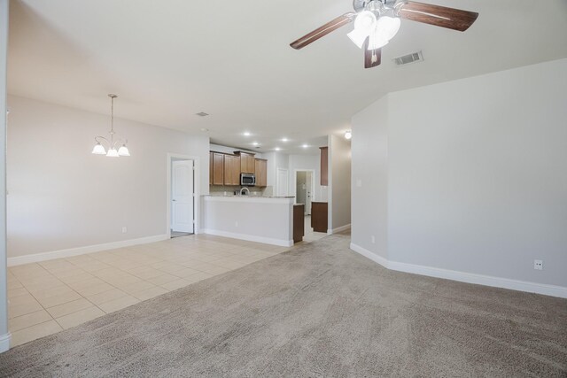 unfurnished living room featuring light tile patterned floors, light carpet, ceiling fan with notable chandelier, visible vents, and baseboards