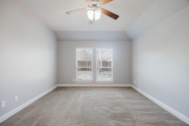 carpeted spare room featuring vaulted ceiling, a ceiling fan, and baseboards