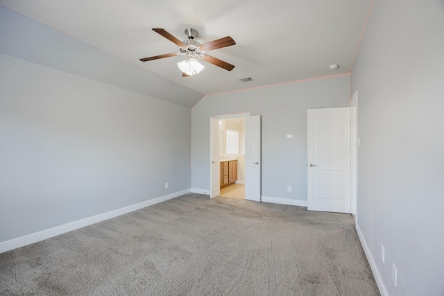 unfurnished bedroom with light carpet, baseboards, visible vents, lofted ceiling, and ensuite bathroom