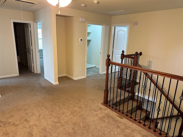 corridor featuring carpet, attic access, baseboards, and an upstairs landing