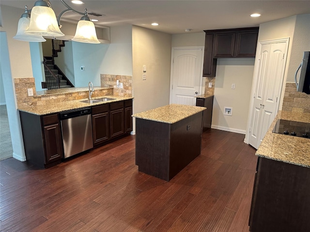 kitchen with stainless steel appliances, dark wood-type flooring, a sink, a kitchen island, and light stone countertops